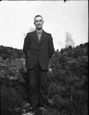 En man vid namn Nils från Kalvhult, Veddige, står ute i en ljungbacke.