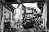 Grävmaskin och lastbil används vid rivning av fastigheten Köpmangatan 4, 1985