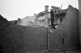 Grävmaskinen har påbörjat rivningen av fastigheten Köpmangatan 4, 1985