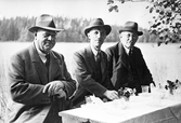 Reproduktion av foto, tre herrar vid ett bord