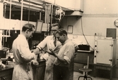 Lennart Karlsson, Tore Halpert och Hans Dahlström står i SOABs laboratorium 1950-tal. Detta låg längst ner vid Gamla torget utmed forsen. Byggnaden är numera riven.