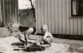 Eva Pettersson (gift Kempe) och kusinen Stina Krantz leker i sandlådan på Torrekulla gård där Eva bor, våren 1947.