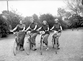 Från Cykelns Dag, anordnad av Monark. Flera olika cyklar visades under dagen i Varberg och flickornas cyklar representerar de nya cyklarna. På flickornas tröjor står MONARK. Från vänster: Henny Lauritzon, Tyra Linder, Lissi Sjöberg, Svea Lundgren. Kontorister på Monark.