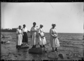 Fem kvinnor vid vattnet.