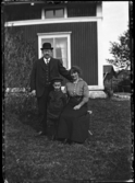 Familjeporträtt; en man, en kvinna och en pojke utanför ett bostadshus.