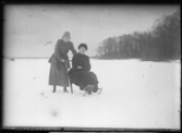 Två kvinnor, vinterklädda, med en sparkstötting.