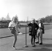 Flickor lutar sig mot staket på Södra Lillåstrandskolans skolgård, 1960-tal