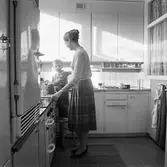 Lars står på en pall med kakburken vid sin mamma i köket i Baronbackarna, 1960