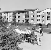 Dagisbarn med dagisfröken vid bord utanför daghem i Baronbackarna, 1960-tal