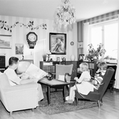 Carl Enbrant läser tidningen medan barnen tittar på TV i vardagsrummet i Baronbackarna, 1960-tal