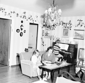 Familjen Enbrant spelar och läser i vardagsrummet i Baronbackarna, 1960-tal