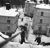 Nils Ström och Lars Westergren på JW plåtslageri skottar snö på taket på järnvägsbostäderna på St Larsgatan 3.