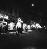 Marknadsbesökare strosar vid butiker på Drottninggatan på marknadsafton, 1967