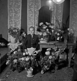 Kvinna sittandes vid blomsterbord.