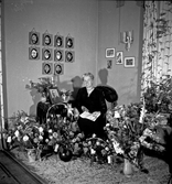 Kvinna sittandes bland blombuketter.