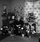 Man sittandes bland blombuketter.