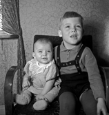 Två barn sittandes i en fåtölj.