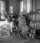 Kvinna sittandes vid blomsterbord.