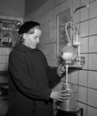 Barbro Johansson häller upp mjölk i sin mjölkkanna med hjälp av en autometer