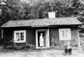 Greta Olsson framför stuga i Yxta i Hovsta, 1984