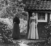 Två kvinnor vid hus i hus i Yxtabacken i Hovsta, ca 1900