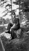 Lennart i uniform sittande på sten i skogsdunge, 1930-tal