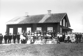 Stor grupp framför hus i Hovsta, 1890-tal