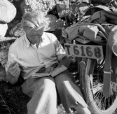 Lennart läser handboken bredvid sin vid motorcykel, 1940-tal