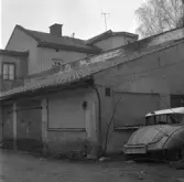 Skrotbil stående vid garage på gården Rudbecksgatan 6, 1971 januari
