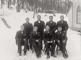 Konfirmandgrupp med en liten grupp pojkar ute i snön vid huvudbyggnaden på räddningshemmet Mäshult, uppförd 1880. Här inrättades då Hallands räddningsinstitution för vanvårdade barn, en uppfostringsanstalt för barn mellan 10 och 15 års ålder.