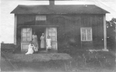 Gruppbild med fem kvinnor och flickor, fotograferade framför dörröppningen på ett hus.
