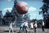 Ungdomar leker med boll på idrottsplan, 1970-tal