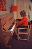 Flicka spelar piano på fritidsgården, 1960-tal