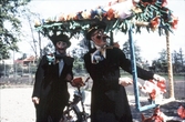 Två välklädda herrar med tandemcykel i Barnens dag-tåget, 1950-tal