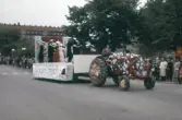 Dansande par blir dragna av traktor i Barnens dag-tåget, 1950-tal