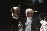 Flicka tittar på utklädda gubbar i Barnens dag-tåg, 1950-tal