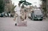 Poserande par med resväska framför lastbilar på Barnens dag, 1950-tal