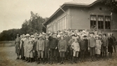 Elever och lärare står utanför gymnastiksalen/samlingssalen, Kålleredskolan cirka 1920.