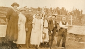 Män och kvinnor står samlade vid någon typ av nybyggnation, okänd plats 1924. Nora Krantz (i ljus, rutig klänning) ses i mitten och längst till höger står Carl Krantz.