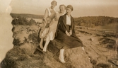 Tre kvinnor poserar sittandes på en berghäll, 1930-tal. I bakgrunden ses en torvtäckt samt Tulebosjön. Kvinnorna är troligtvis arbetskamrater från Stretereds vårdhem.