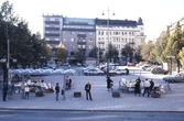 Busshållplats och grönsaksstånd framför parkering på Järntorget, 1987