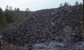 Flätsbo gruva. Stor hög av bruten sten. Skog i bakgrunden.