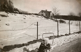 Eva Pettersson (född 1944, gift Kempe) sitter i kärran i det snötäckta Sagered, februari 1946. Familjen är på väg till mormor som bor i Stretered.