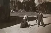 Det är vår och dockorna ska ut. En okänd flicka samt  Eva (gift Kempe) Pettersson leker på grusplanen vid Stretereds personalbostad i Tulebo1946. Evas mormor, Nora Krantz, vädrar madrasser i bakgrunden.
Den ljusa flickan finns även med på foto: 2023_0093 samt 2023_0098.