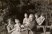 Familjen sitter samlad utomhus, Stretered personalbostad 1946. Från vänster: Rosa Pettersson (född Krantz), Eva Pettersson, Nora Krantz, Carl Krantz (närmast), Edit Krantz samt Bror 