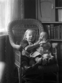 Gustaf Björkströms söner Bo med Åke som liten baby i en korgstol framför en bokhylla.
