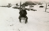 Eva Pettersson (född 1944, gift Kempe) åker kälke utanför huset, Torrekulla gård 1947.