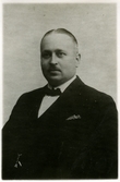 Porträtt på Anton Edgren i kostym och fluga. Fabrikör och ägare av Chokladfabriken i Kalmar, född 1882, död 1944. Ägde sedan 1920 villan Monte Cavallo, Biskopsgatan 5, Kalmar.