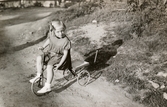 Eva Pettersson (gift Kempe) cyklar på en trehjuling, Gamlehagsvägen i Torrekulla 1948.
