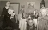 Julafton på övervåningen hemma hos familjen Pettersson på Gamlehagsvägen 17, Torrekulla år 1950. Från vänster ses Nora Krantz (1879 - 1955), Jultomten?, Karl Holmberg och Carl Krantz (1880 - 1956). I förgrunden ses systrarna Karin Pettersson (född 1947, gift Hansson) och Eva (född 1944, gift Kempe), barnbarn till Nora och Carl.